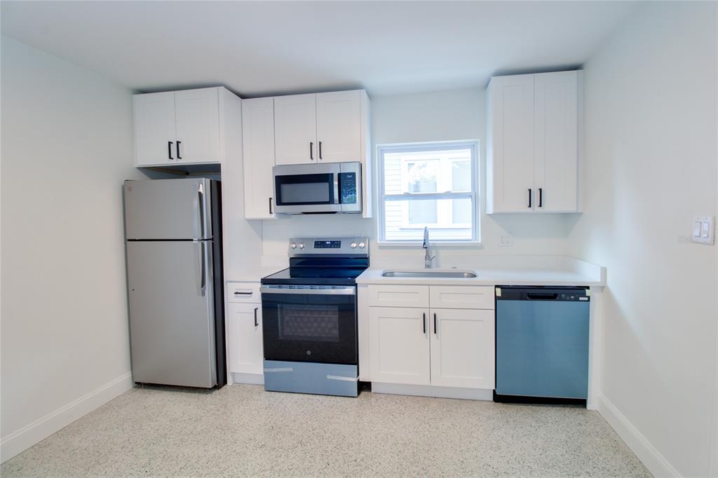 A kitchen featuring white cabinets, stainless steel appliances, a window, and light-colored speckled flooring — 1618 INDIANA AVENUE, WINTER PARK, FL