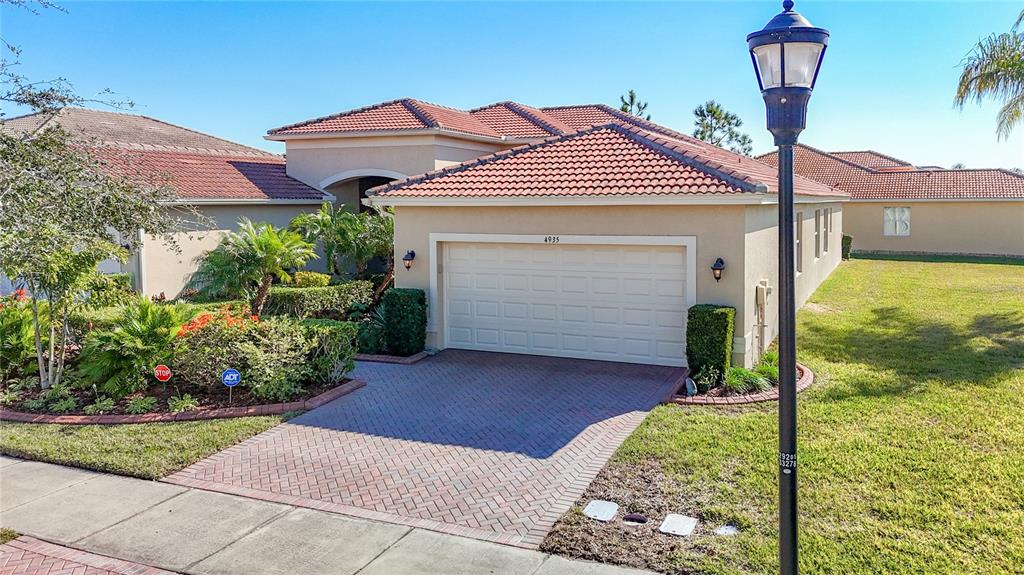 A beige house with a red tile roof and a brick driveway under a clear sky — 4935 MARBLE SPRINGS CIRCLE, WIMAUMA, FL