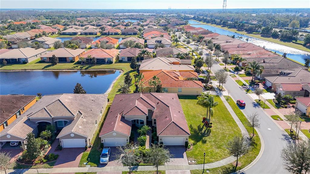 An aerial view shows a suburban neighborhood with single-family homes, a lake, and streets — 4935 MARBLE SPRINGS CIRCLE, WIMAUMA, FL
