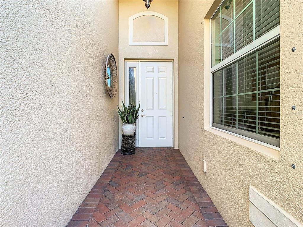 A brick-paved entryway leads to a white front door with a side window — 4935 MARBLE SPRINGS CIRCLE, WIMAUMA, FL