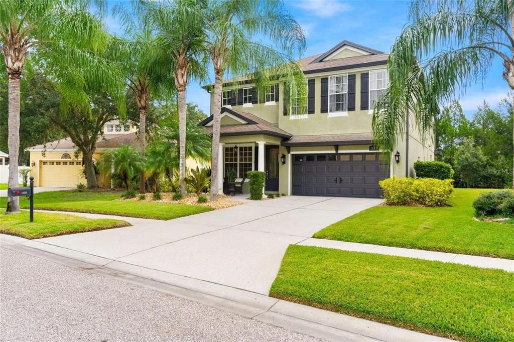 A two-story house with a green stucco exterior, dark shutters, and a two-car garage — 1122 NASHVILLE DRIVE, WESLEY CHAPEL, FL