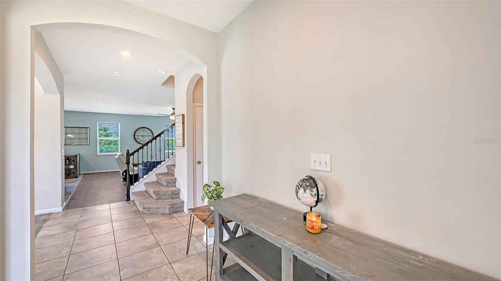 A tiled entryway leads to a carpeted staircase and a living area with light-colored walls — 6008 113TH TERRACE E, PARRISH, FL