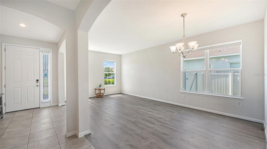 An open dining area features gray wood-look flooring, a chandelier, and a large window — 6008 113TH TERRACE E, PARRISH, FL