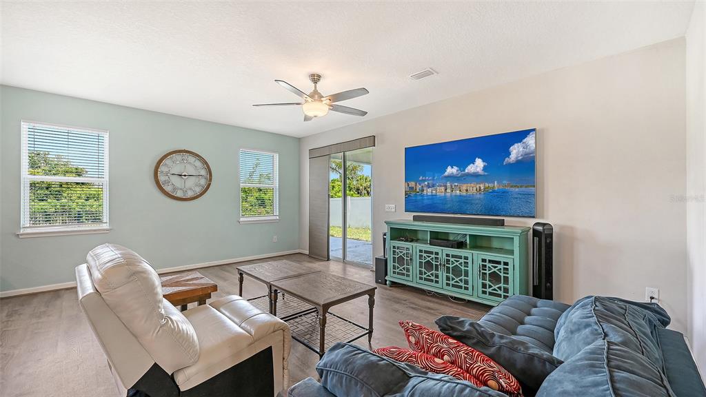 A living room features a light blue accent wall, a television, and a teal console — 6008 113TH TERRACE E, PARRISH, FL