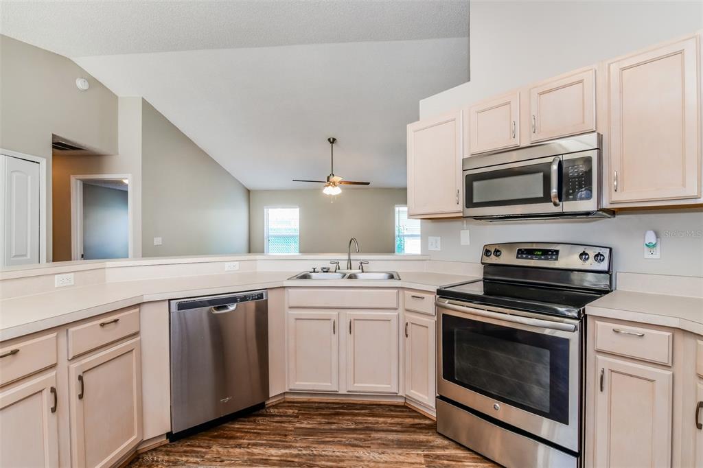 A kitchen features light wood cabinets, stainless steel appliances, and a double sink — 8615 CAVENDISH DRIVE, KISSIMMEE, FL