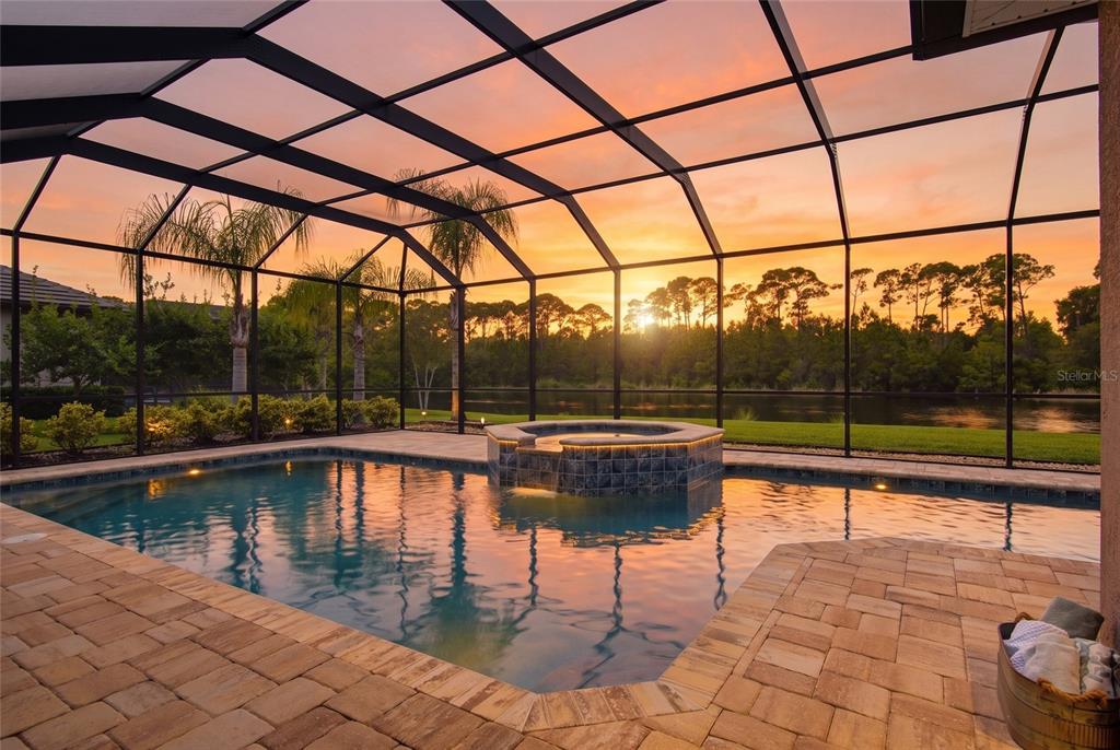 A screened-in swimming pool and spa at sunset with a view of a lake — 206 WILLOW OAK WAY, PALM COAST, FL