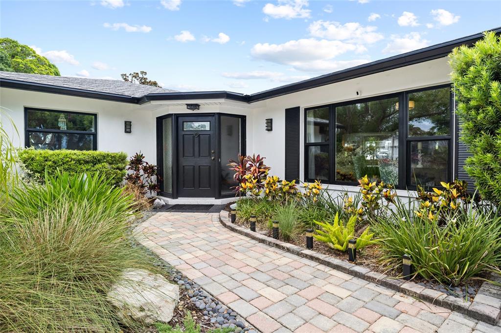 A paved walkway leads to the front entrance of a white house with black trim — 14006 81ST AVENUE, SEMINOLE, FL