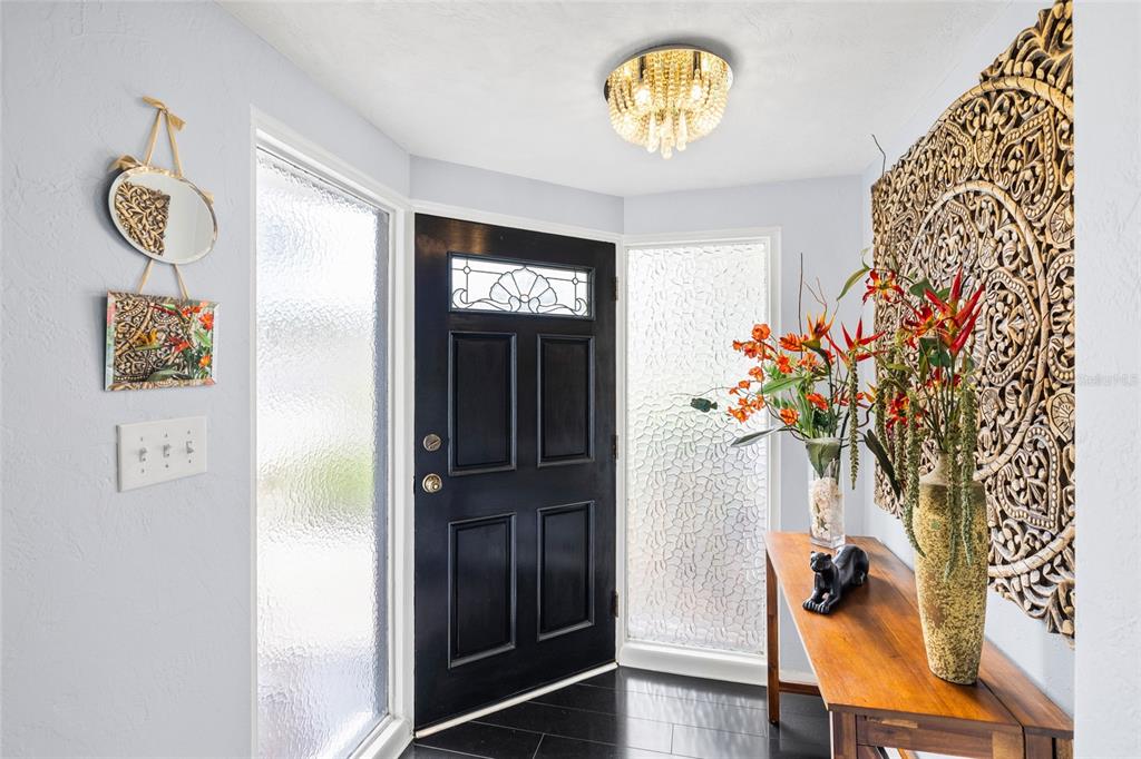 An entryway features a black front door, a crystal light fixture, and a wooden console table — 14006 81ST AVENUE, SEMINOLE, FL