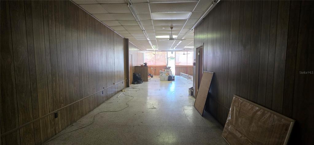 An empty commercial space features wood-paneled walls, a drop ceiling, and a light-colored floor — 1168 JASPER STREET, LARGO, FL
