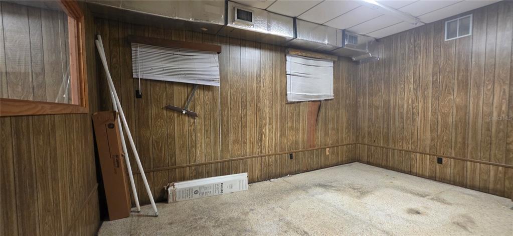 An unfinished basement room features wood-paneled walls, a drop ceiling, and exposed ductwork — 1168 JASPER STREET, LARGO, FL