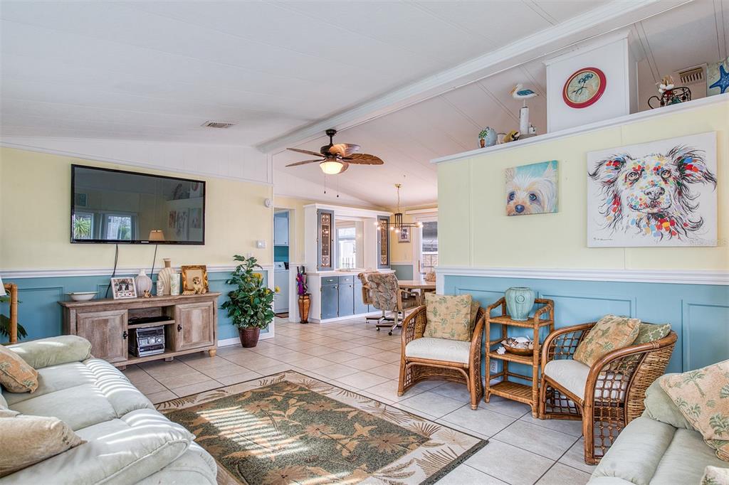 A living room with light yellow and blue walls, tile floors, and wicker furniture — 83 PELICAN DRIVE N, OLDSMAR, FL