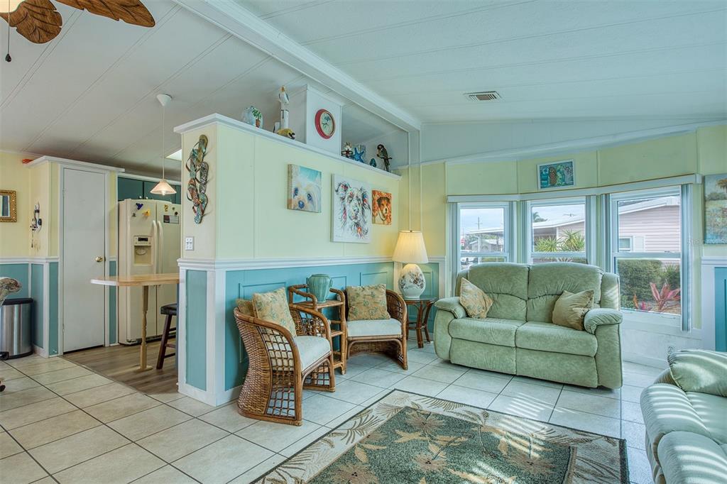 A living room features light yellow walls, blue wainscoting, tile flooring, and a green sofa — 83 PELICAN DRIVE N, OLDSMAR, FL