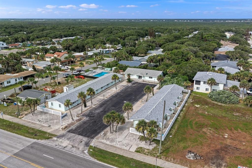 An aerial view shows two long buildings flanking a central parking lot with palm trees — 1708 S ATLANTIC AVENUE, NEW SMYRNA BEACH, FL