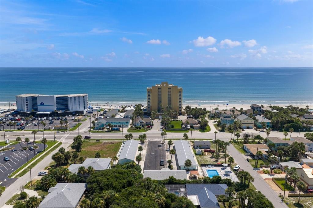 An aerial view shows a rectangular swimming pool surrounded by a paved patio and lounge chairs — 1708 S ATLANTIC AVENUE, NEW SMYRNA BEACH, FL