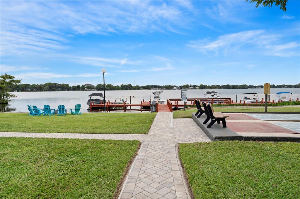A paved walkway leads to a wooden boat dock on a lake with lawn chairs — 151 N ORLANDO AVENUE UNIT 261, WINTER PARK, FL