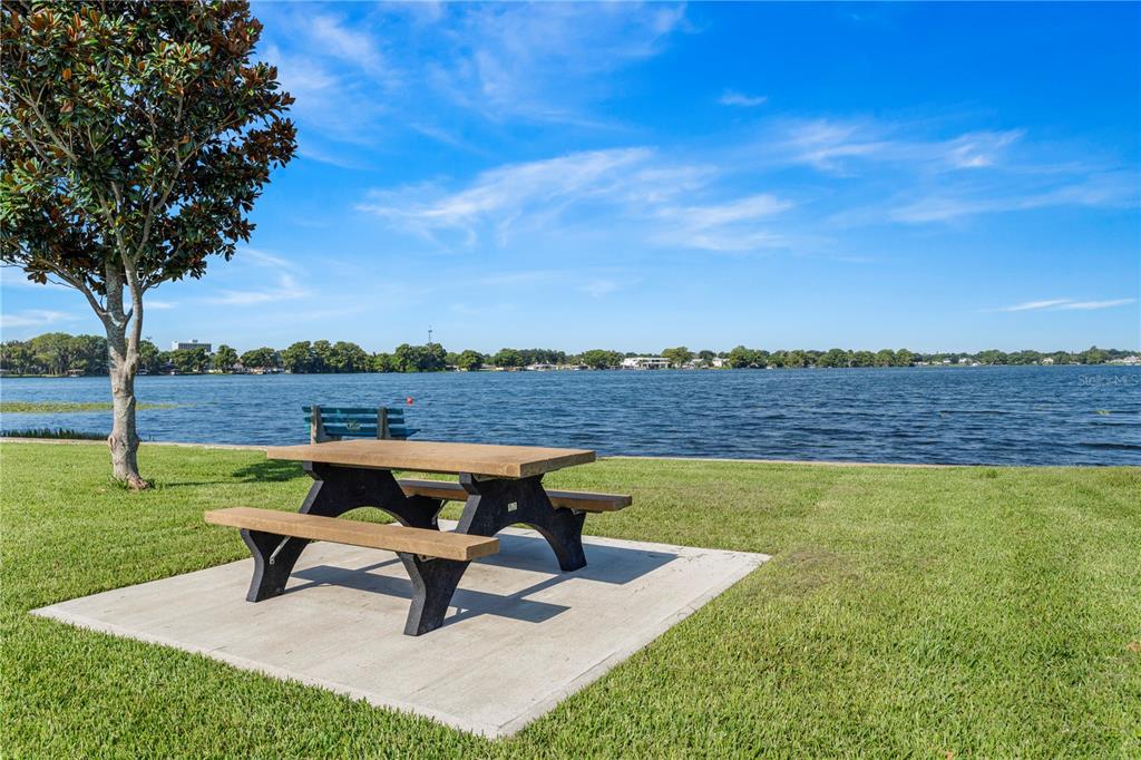 A picnic table sits on a concrete pad near a lake under a blue sky — 151 N ORLANDO AVENUE UNIT 261, WINTER PARK, FL