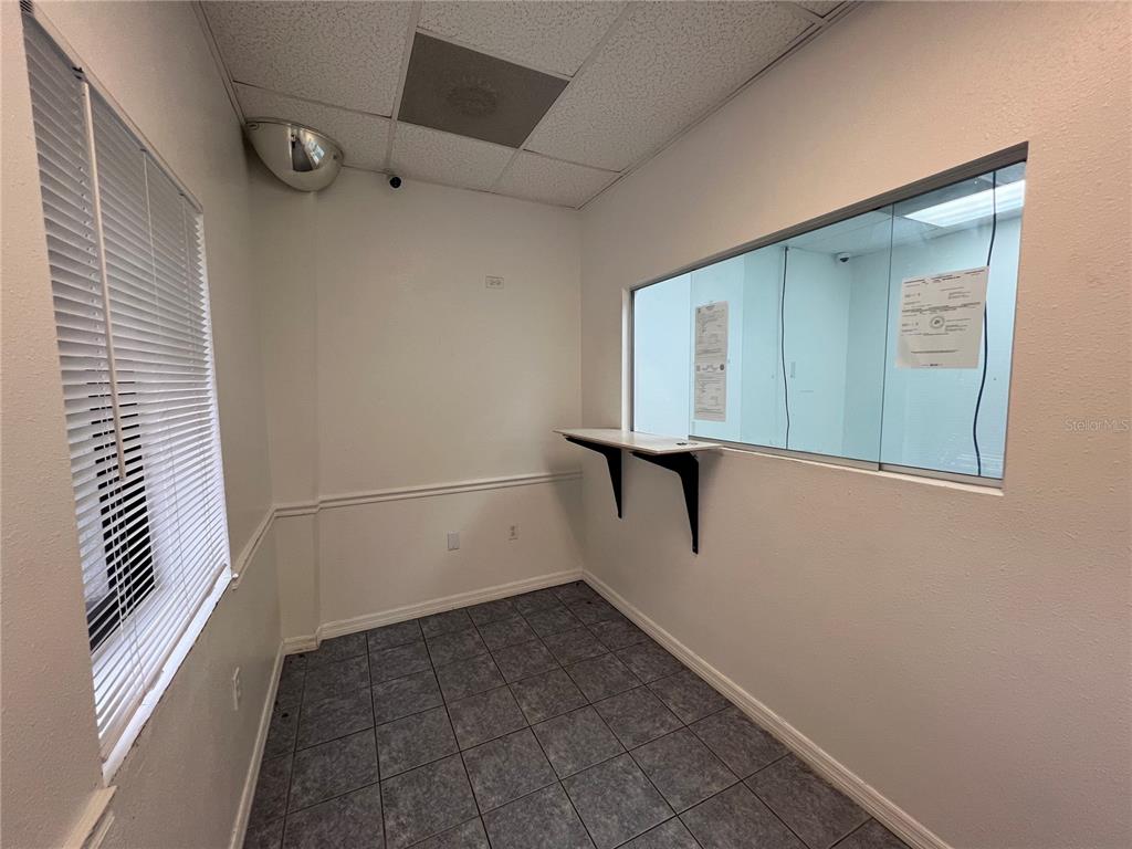 A small office space features tiled flooring, a windowed partition, and a wall-mounted counter — 7216 CHANCERY UNIT 100, ORLANDO, FL