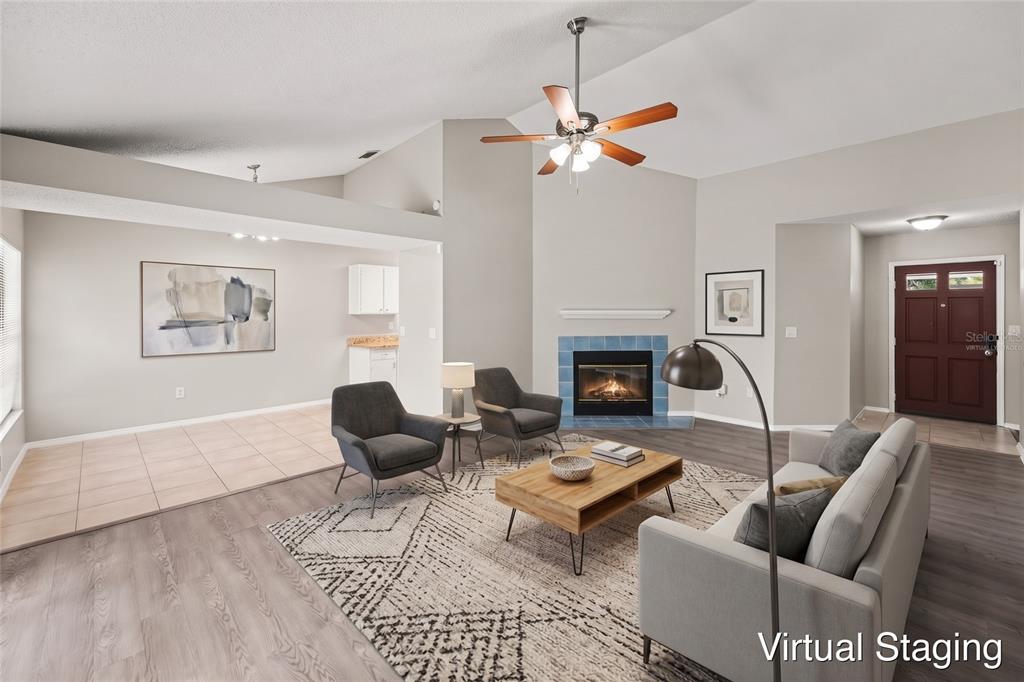 A living room with wood-look flooring, a tiled fireplace, and an adjacent tiled dining area — 8739 OSAGE DRIVE, TAMPA, FL