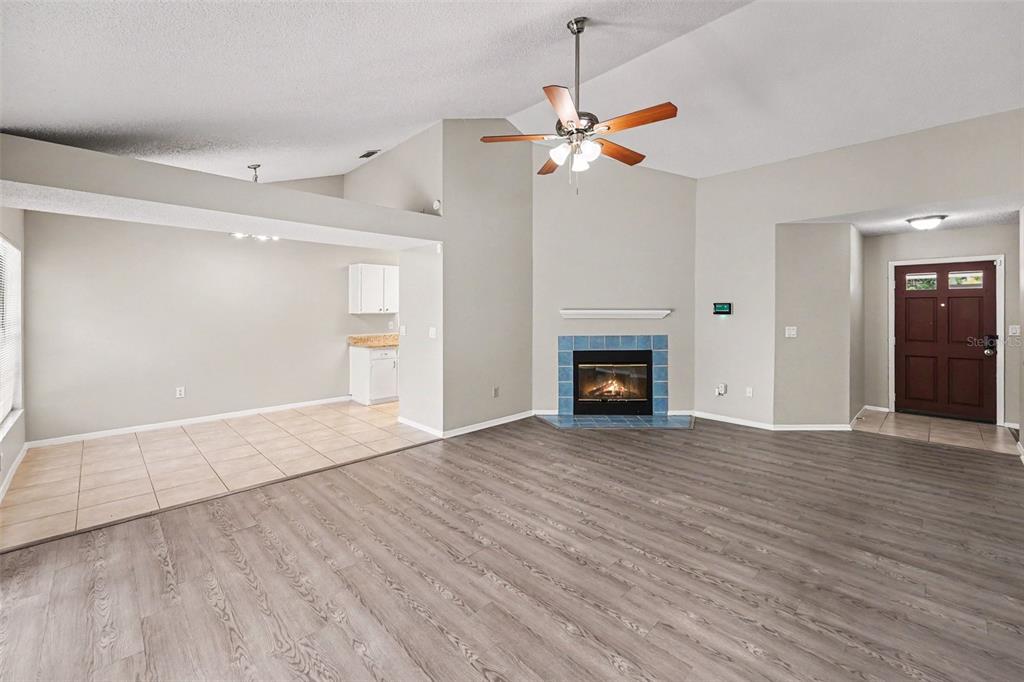 A living room features wood-look flooring, a vaulted ceiling, and a blue-tiled fireplace — 8739 OSAGE DRIVE, TAMPA, FL