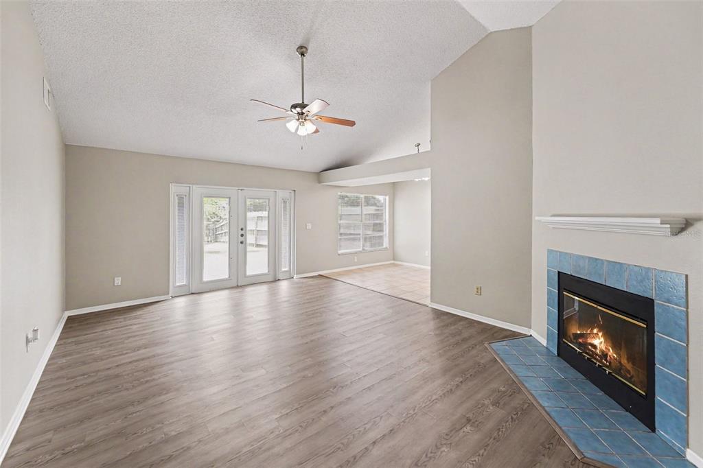 An open-concept kitchen with tile flooring transitions into a living area with wood-look flooring — 8739 OSAGE DRIVE, TAMPA, FL