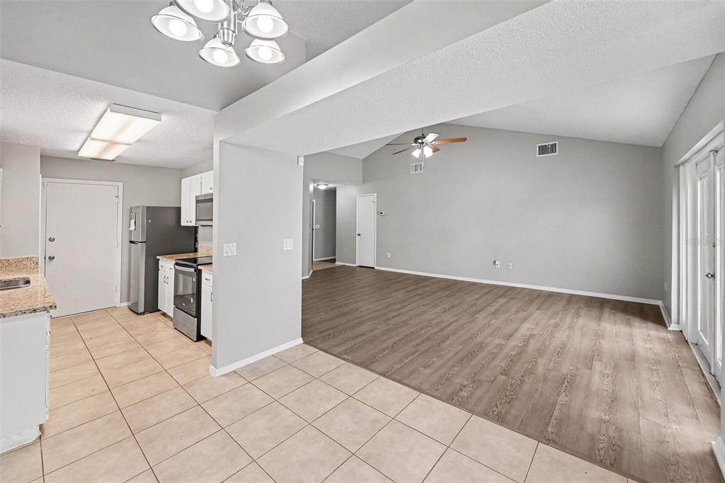 A galley kitchen features white cabinets, granite countertops, stainless steel appliances, and tile flooring — 8739 OSAGE DRIVE, TAMPA, FL