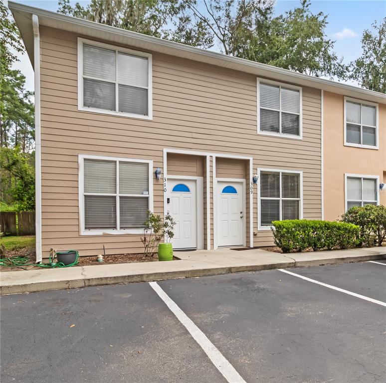 A two-story tan townhouse exterior features white trim, two front doors, and a parking lot — 4415 SW 34TH STREET UNIT 309, GAINESVILLE, FL
