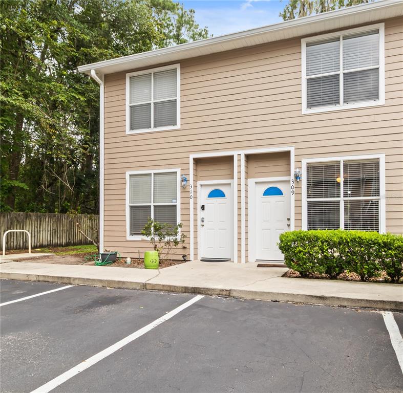 A two-story tan building features two adjacent white front doors and a paved parking lot — 4415 SW 34TH STREET UNIT 309, GAINESVILLE, FL