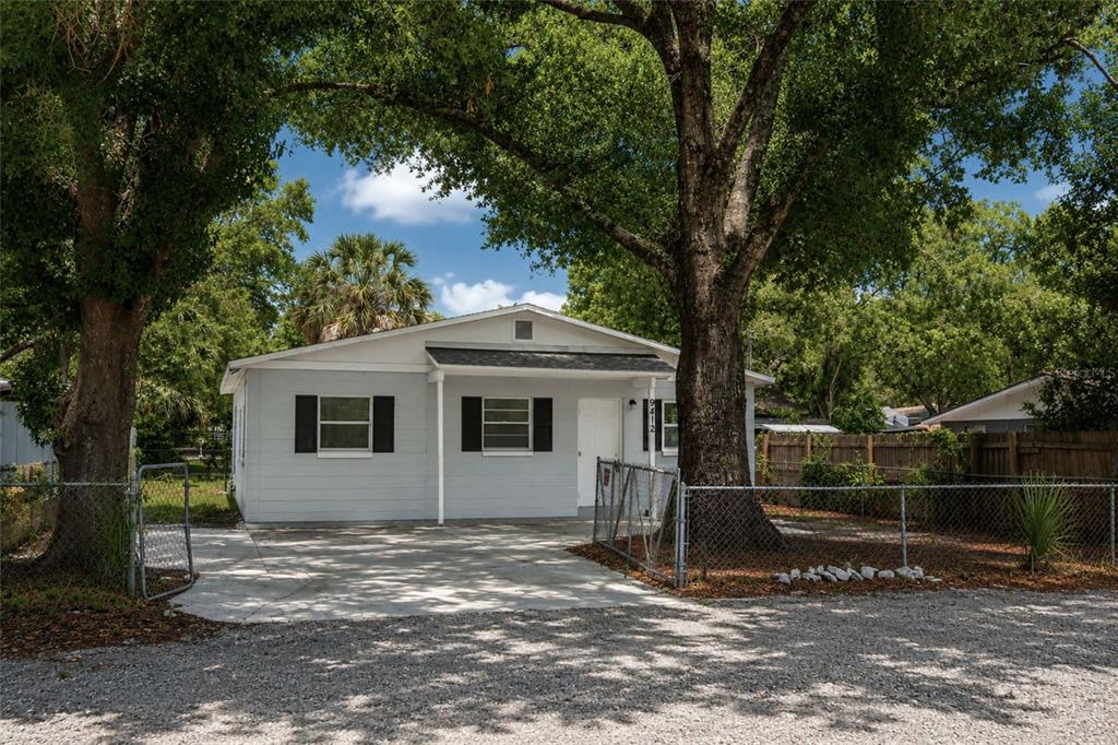A light blue single-story house with a concrete driveway and large trees in the front yard — 9412 N ELMER STREET, TAMPA, FL