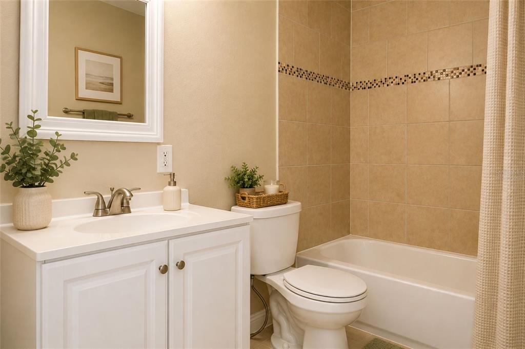 A bathroom features a white vanity, a toilet, and a bathtub with tan tiled walls — 9412 N ELMER STREET, TAMPA, FL