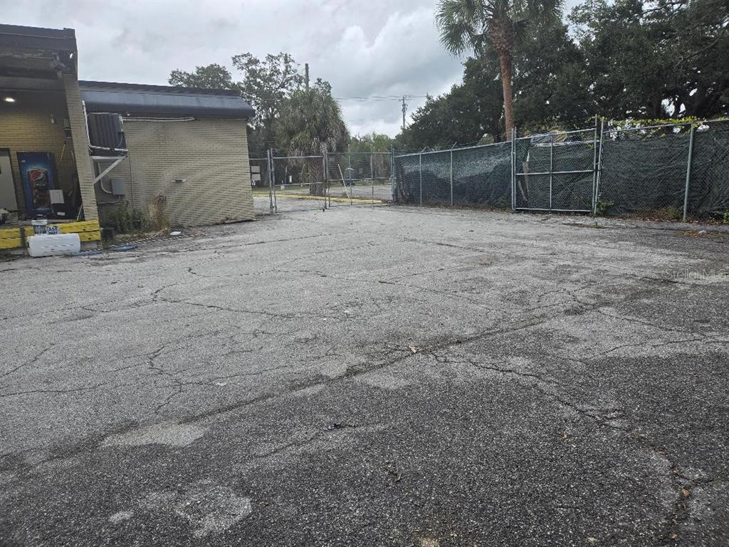 An exterior view of a paved parking lot next to a brick building and fence — 10517 RIVERVIEW DRIVE, RIVERVIEW, FL