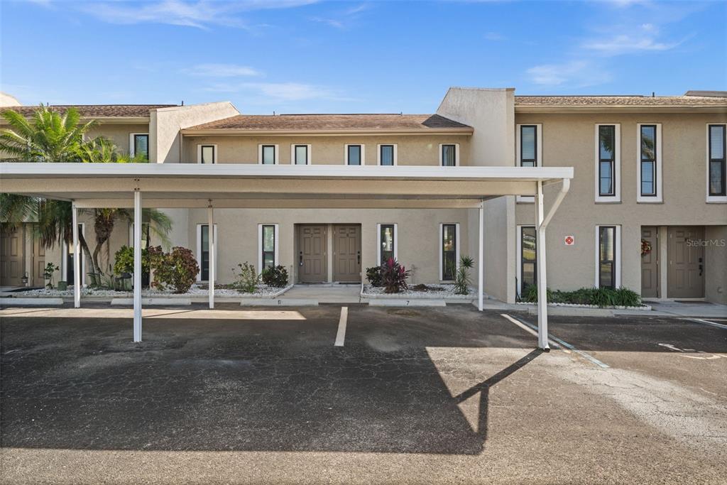 A two-story townhouse exterior features a covered parking area and a paved driveway — 4803 SW SANTA BARBARA COURT UNIT 8, CAPE CORAL, FL