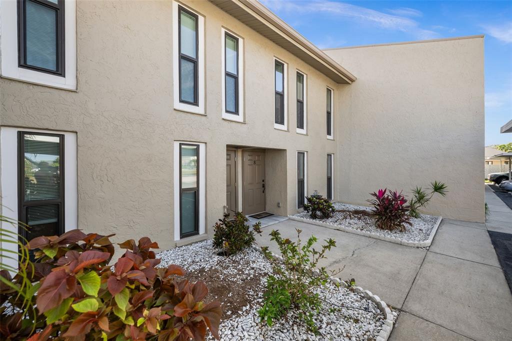 The exterior of a two-story tan stucco building features multiple windows and a front entrance — 4803 SW SANTA BARBARA COURT UNIT 8, CAPE CORAL, FL