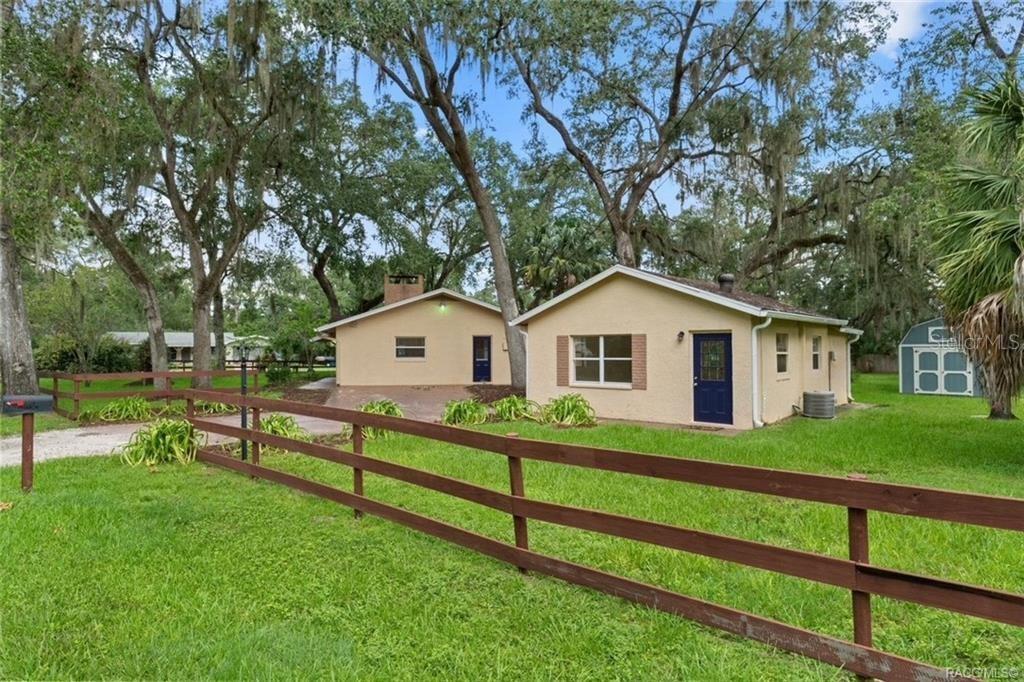 Two small, tan-colored houses sit on a grassy lot behind a brown wooden fence — 4929 E SHADY ACRES DRIVE, INVERNESS, FL