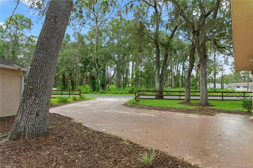 A concrete driveway leads toward a wooden fence and trees in front of a house — 4929 E SHADY ACRES DRIVE, INVERNESS, FL