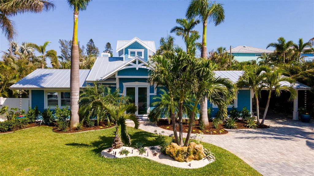 A blue single-story house with a metal roof and palm trees in the front yard — 403 75TH STREET, HOLMES BEACH, FL