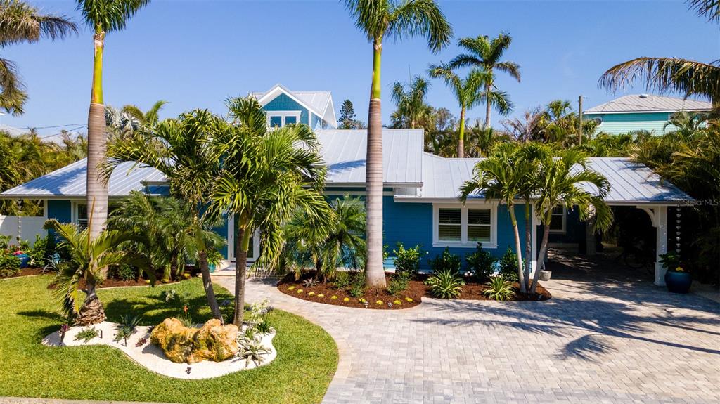A blue house with a metal roof and palm trees sits behind a paved driveway — 403 75TH STREET, HOLMES BEACH, FL