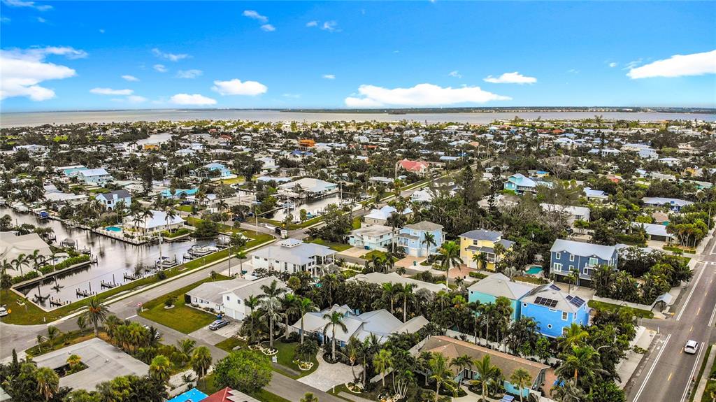 An aerial view shows a coastal neighborhood with houses, palm trees, and a canal — 403 75TH STREET, HOLMES BEACH, FL