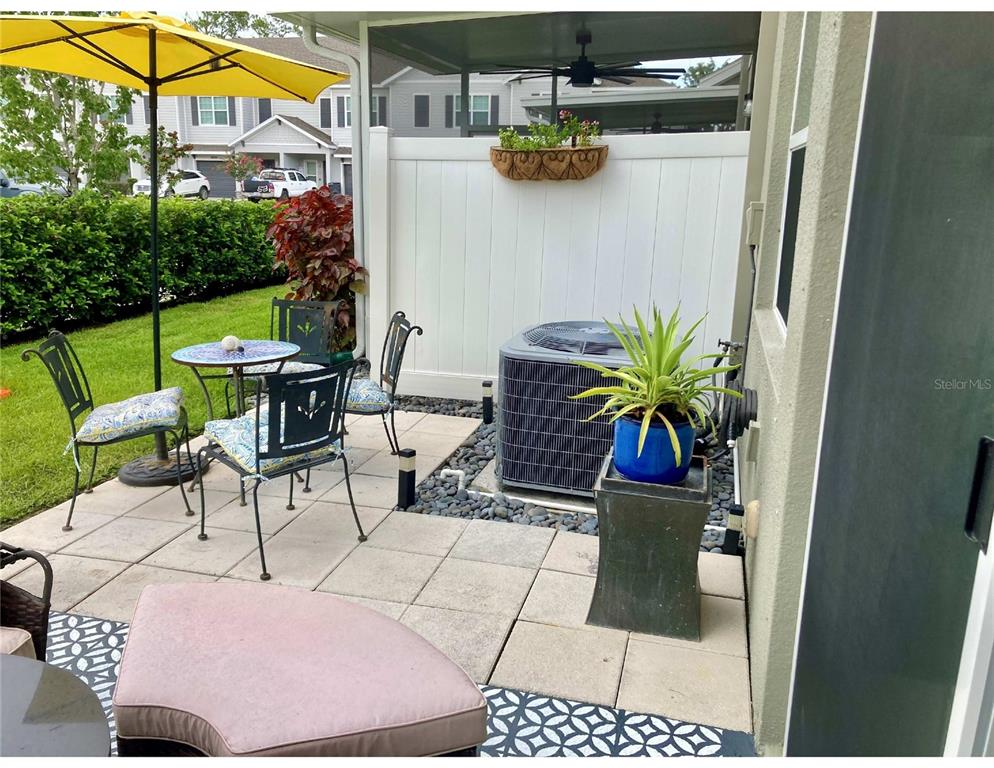 A patio features a dining set, an umbrella, an air conditioning unit, and potted plants — 10824 QUICKWATER COURT, RIVERVIEW, FL