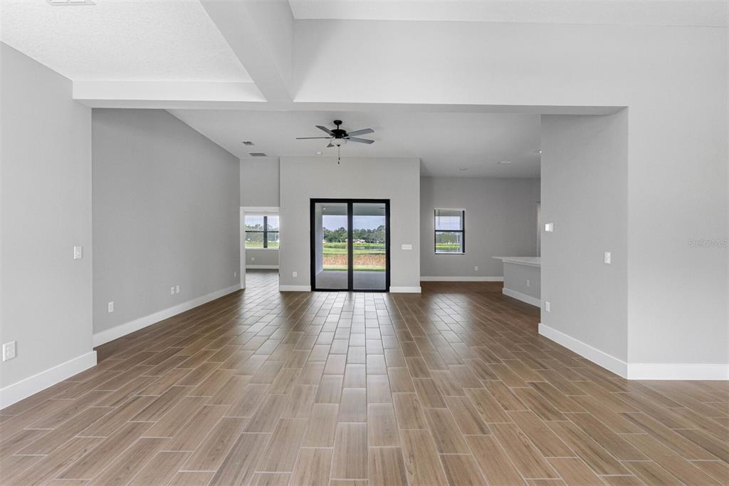 An open-concept living area features wood-look tile flooring, a ceiling fan, and sliding glass doors — 13509 WALDEN SHEFFIELD ROAD, DOVER, FL
