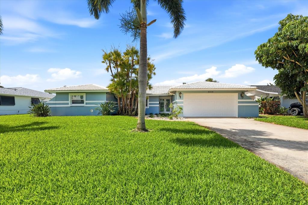 A light blue house exterior features a double glass front door and a stone walkway — 8008 13TH AVENUE S, ST PETERSBURG, FL