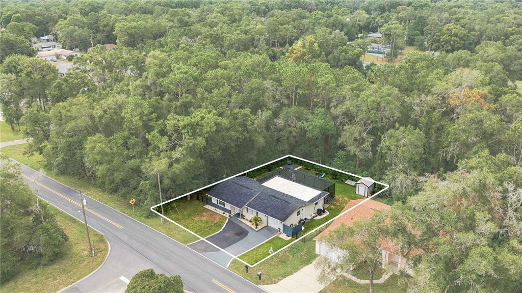 An aerial view shows a single-story house with a pool enclosure and a fenced yard — 221 E INVERNESS BOULEVARD, INVERNESS, FL