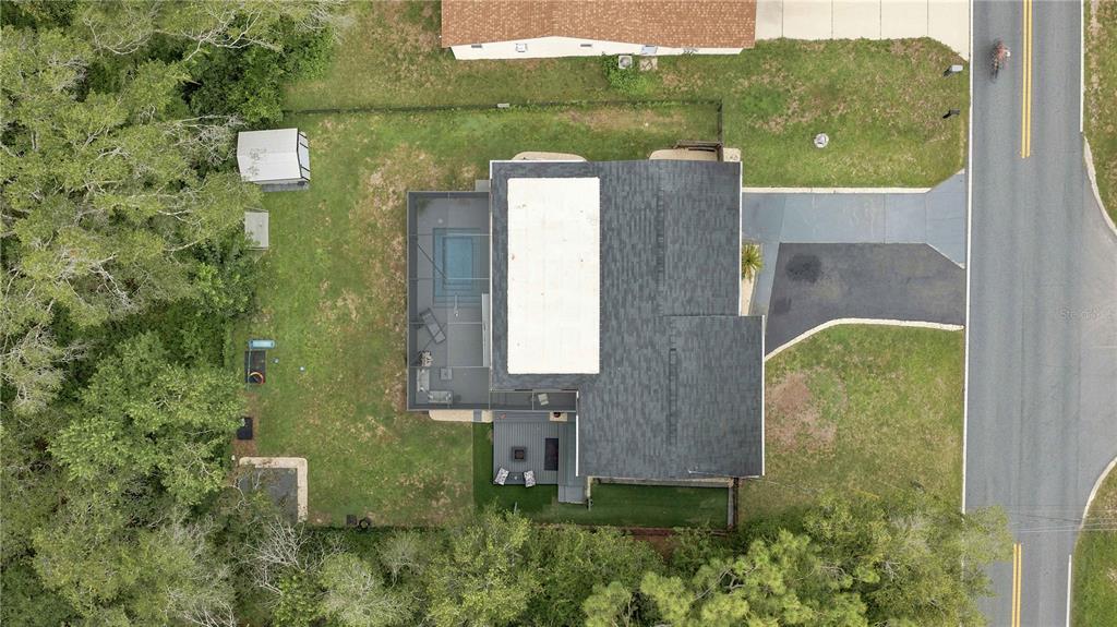 An aerial view shows a house with a screened pool enclosure and a backyard — 221 E INVERNESS BOULEVARD, INVERNESS, FL