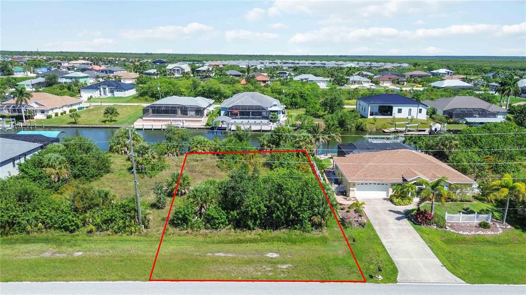 An aerial view shows a vacant, rectangular residential lot outlined in red next to a house — 8633 CALUMET BOULEVARD, PORT CHARLOTTE, FL