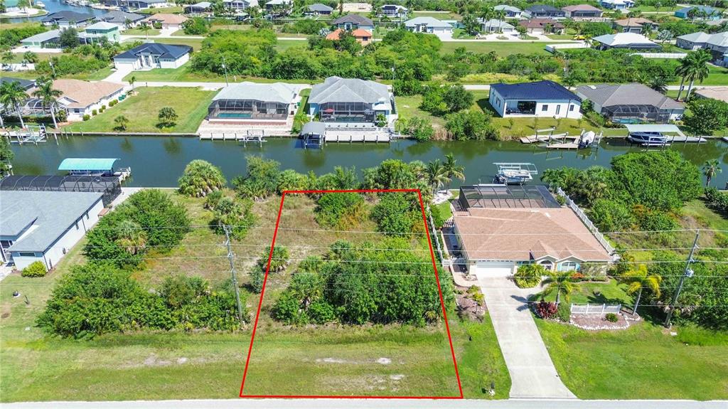 An aerial view shows a vacant, rectangular residential lot outlined in red next to a house — 8633 CALUMET BOULEVARD, PORT CHARLOTTE, FL