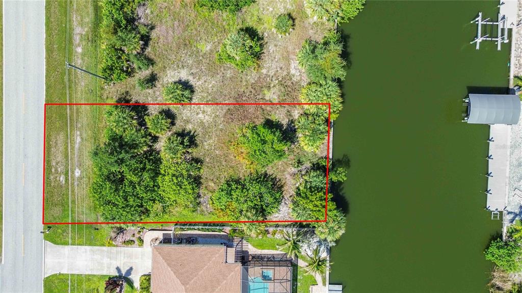 An aerial view shows a rectangular vacant lot bordered by a road and a canal — 8633 CALUMET BOULEVARD, PORT CHARLOTTE, FL