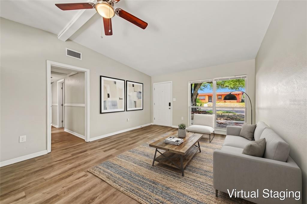 An empty room with light-colored walls, wood-look flooring, a white entry door, and a window — 5909 WOLF ROAD, ORLANDO, FL
