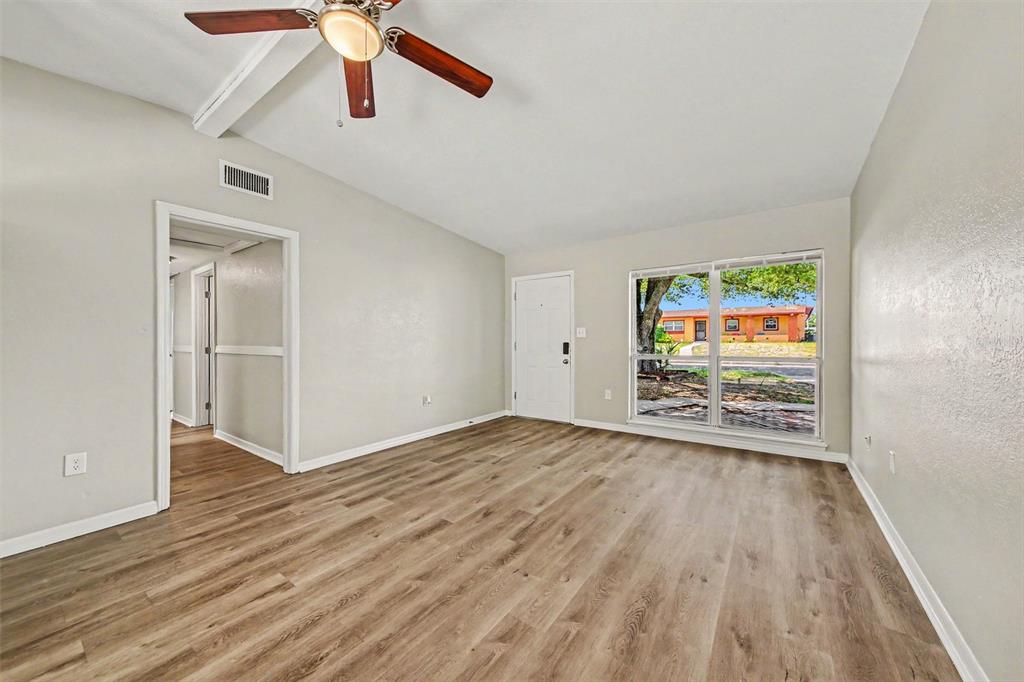 An empty living room features light-colored walls, wood-look flooring, a ceiling fan, and sliding doors — 5909 WOLF ROAD, ORLANDO, FL