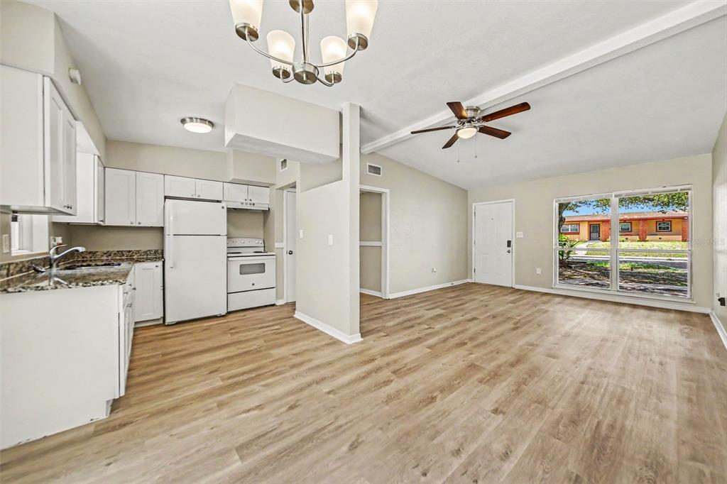 An empty living room features light-colored walls, wood-look flooring, a ceiling fan, and large windows — 5909 WOLF ROAD, ORLANDO, FL