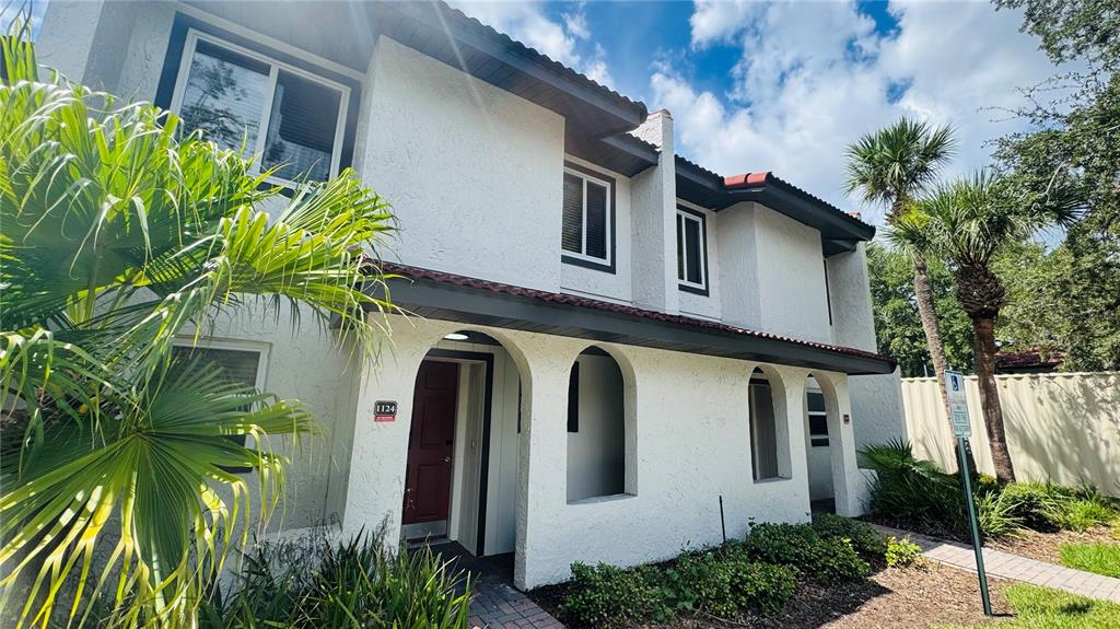 A two-story white stucco townhouse exterior features arched entryways and a red front door — 1124 SPACEPORT COURT, KISSIMMEE, FL