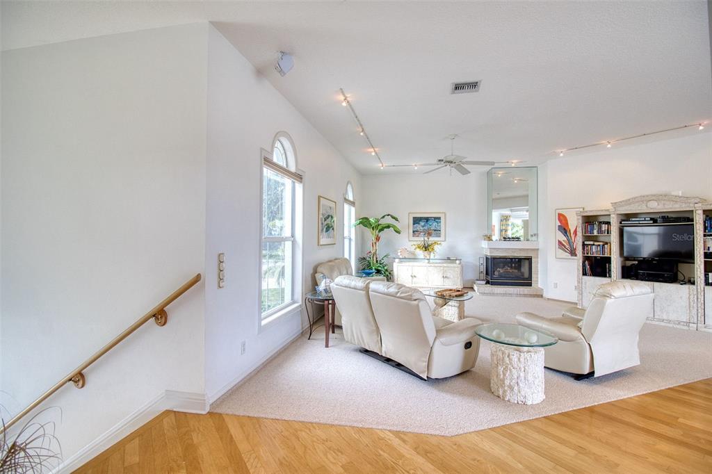 A living room with beige carpet, white leather furniture, a fireplace, and hardwood flooring — 131 SANDS POINT DRIVE, TIERRA VERDE, FL